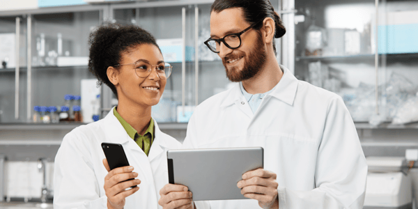 Woman and Man Scientists smiling and holding a tablet and phone